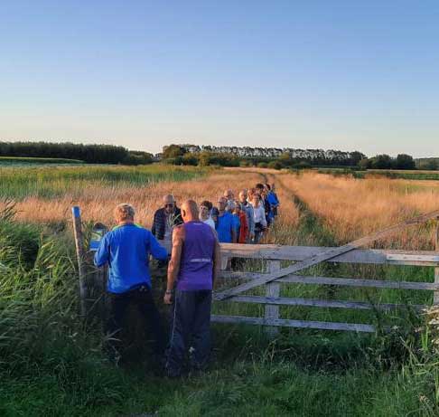 Groep bij een houten hek aan het begin van een natuurwandeling